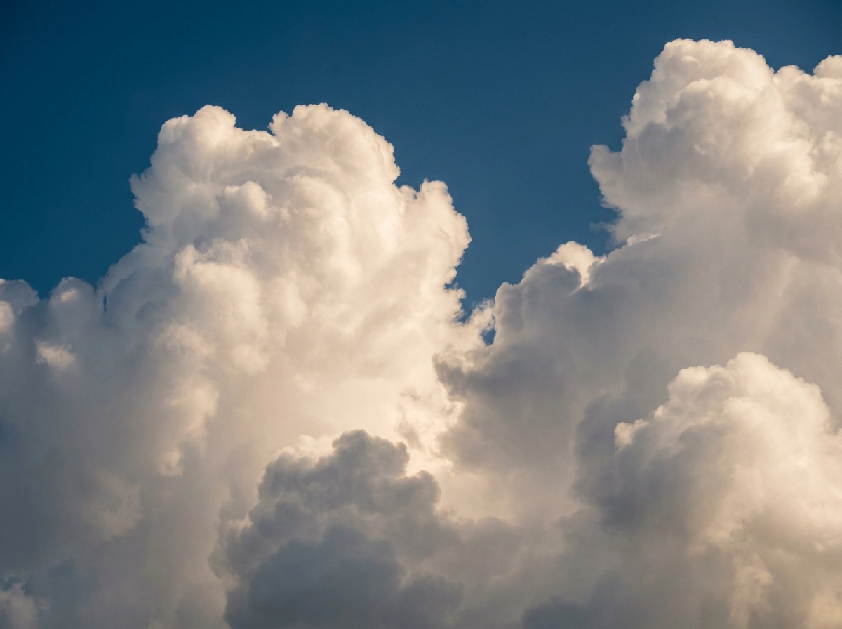 Fluffy white clouds floating in a blue sky, realistic cloud volume and texture, natural sunlight, soft shadows, atmospheric depth, cinematic sky photography, ultra high resolution